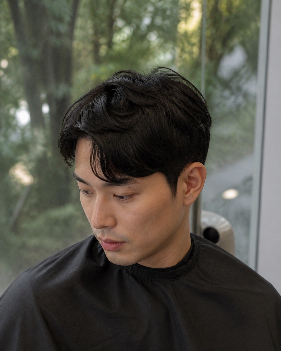 An Asian man with a soft textured Korean perm and side-swept fringe, styled at MANE Hair Experience Singapore