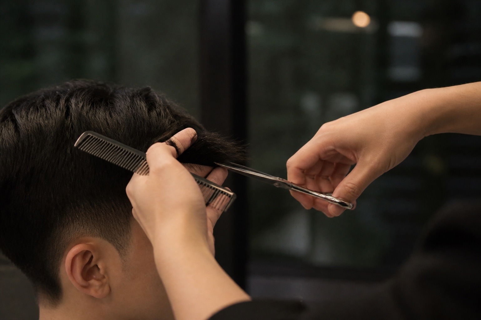 A director-stylist cutting a man's hair in the two-chair room at MANE Hair Experience, Far East Plaza Singapore